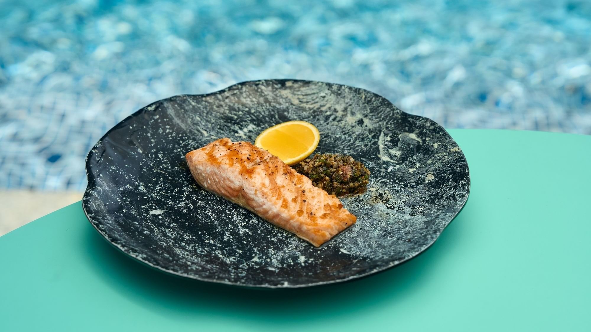 Salmon dish served with a slice of lemon in Malibu Deck Pool Bar at Paramount Hotel Dubai