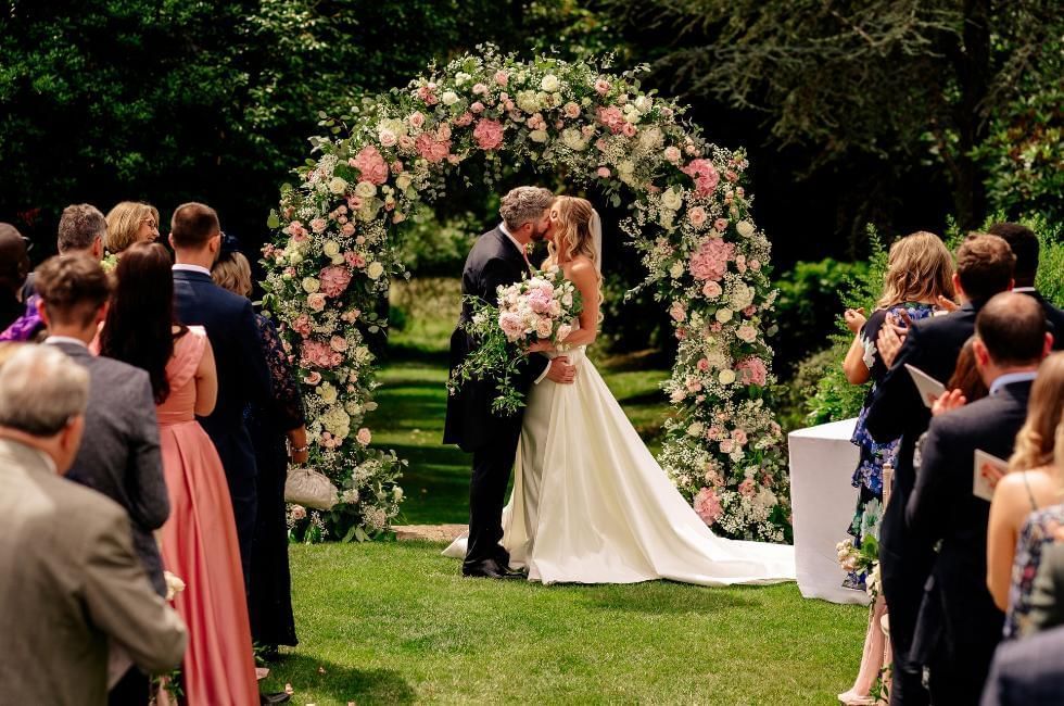 Couple kissing during their outdoor wedding ceremony at Gorse Hill one of the best Surrey Wedding Venues