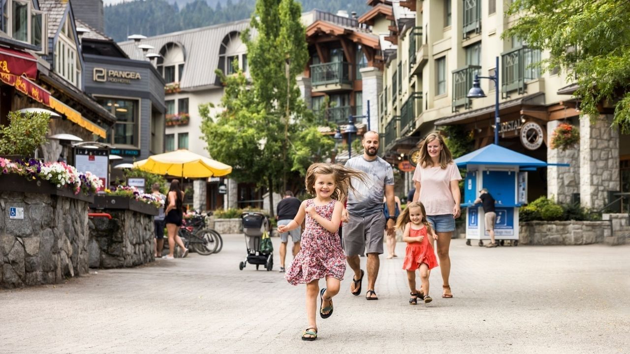 Family enjoying spring activities in Whistler Village with kids running ahead.