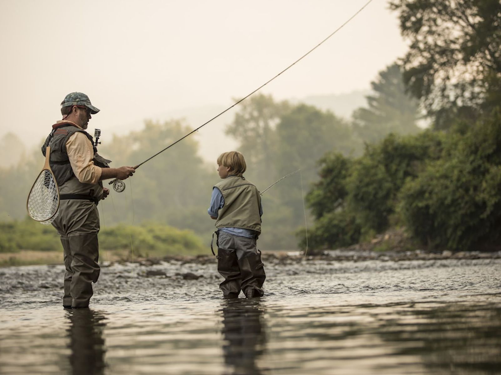 A man and a kid fishing at the river near Topnotch Stowe Resort