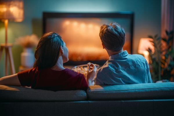 Happy family watching TV, movies in the evening at home. Couple spending time together.