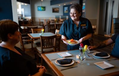 Waitress serving a salad to guests dining at Gales Restaurant in Rodd Grand Yarmouth, a top choice among hotels in Yarmouth