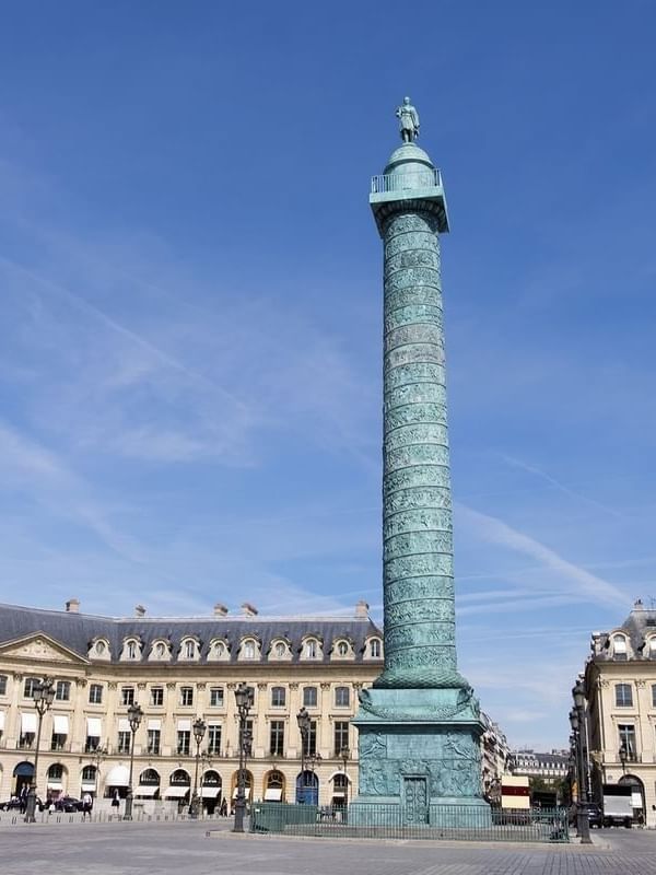 Vendôme Column standing tall by classic stone buildings under a bright blue sky near Hotel Westminster Paris