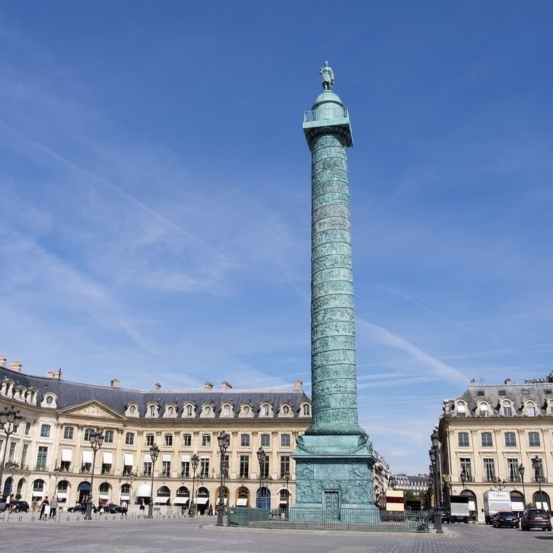 Vendôme Column standing tall by classic stone buildings under a bright blue sky near Hotel Westminster Paris