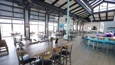 Indoor dining area with a bar counter, filled with natural light in the Bar & Grill at Off Shore Resort