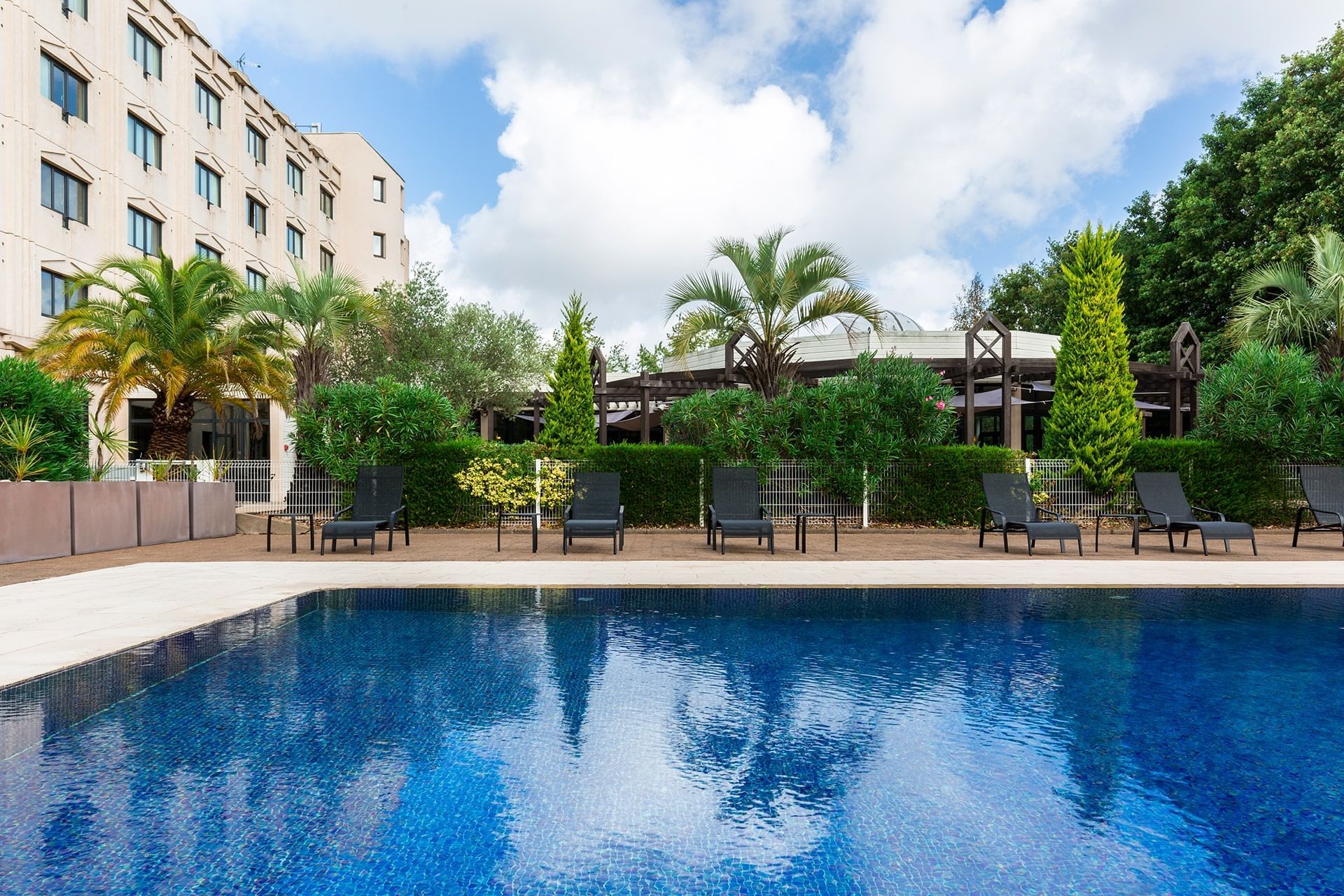 Lounges by the outdoor pool area at Oceania Nantes Aéroport