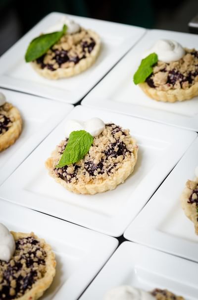 Close up of delicious berry crumble tarts garnished with mint leaves and cream served at The Stanley Hotel