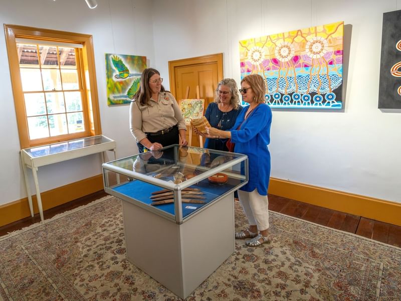 Three women examining artifacts in the Kew-Y-Ahn Aboriginal Gallery.