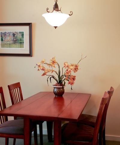 A dining table with wooden chairs and a floral centerpiece in The suite at The Pointe at Castle Hill