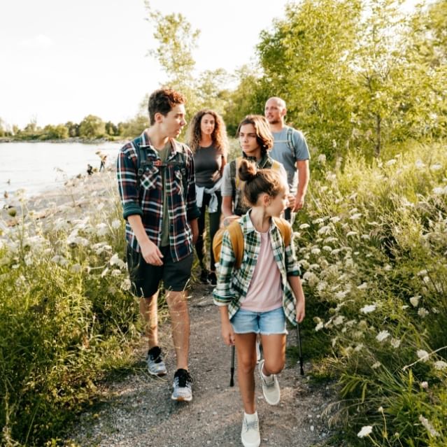 Family Hiking Along Path By River near Chase on The Lake