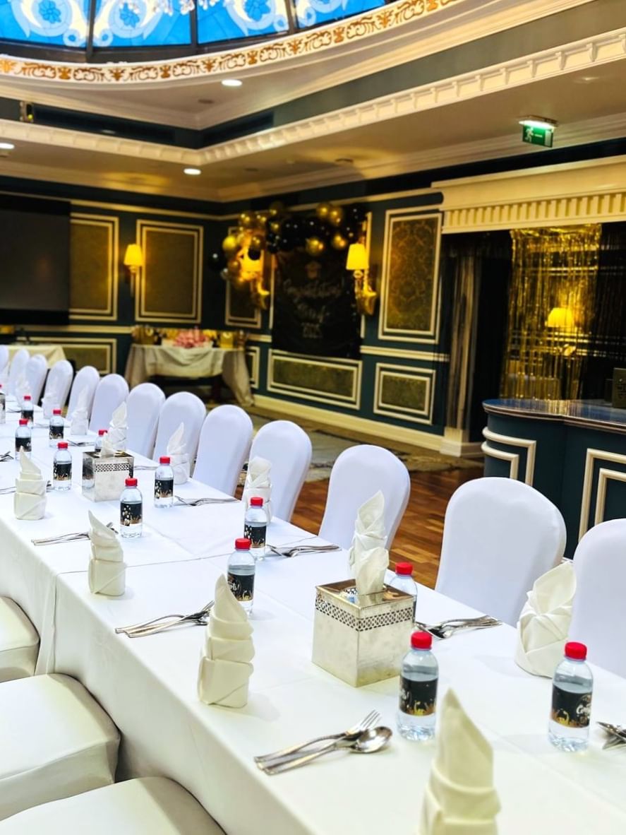 Elegantly set long banquet table with white chairs and decor in Blue Room at Warwick Doha.