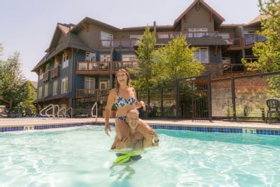 Man carrying his wife on shoulders in the Pool at Blackstone Mountain Lodge at Blackstone Mountain Lodge