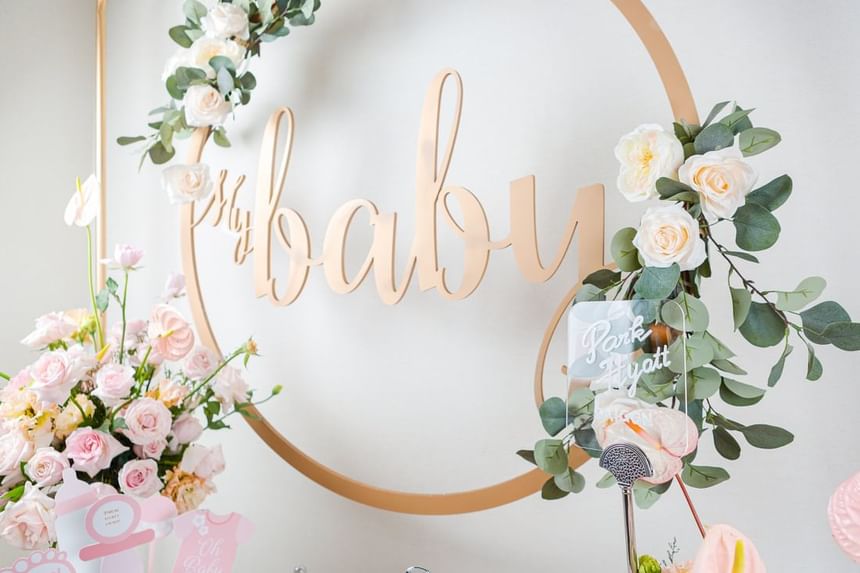 Decorative wall with a My Baby sign, surrounded by greenery & pink flowers for a baby shower celebration at Park Hyatt Saigon
