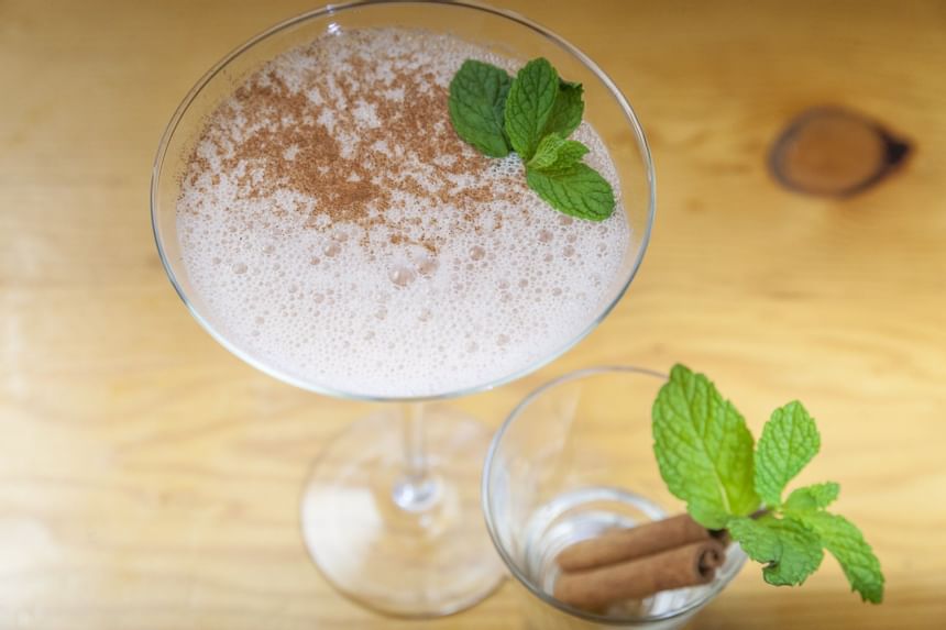 drink in martini glass with cinnamon sticks