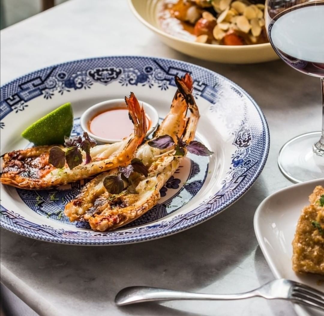 grilled king prawns at Elysium Hotels on a patterned plate with chili sauce and lime on a marble table