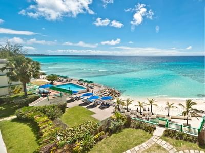 Aerial view of tropical Rostrevor Hotel with a pool overlooking a clear blue sea and sun loungers