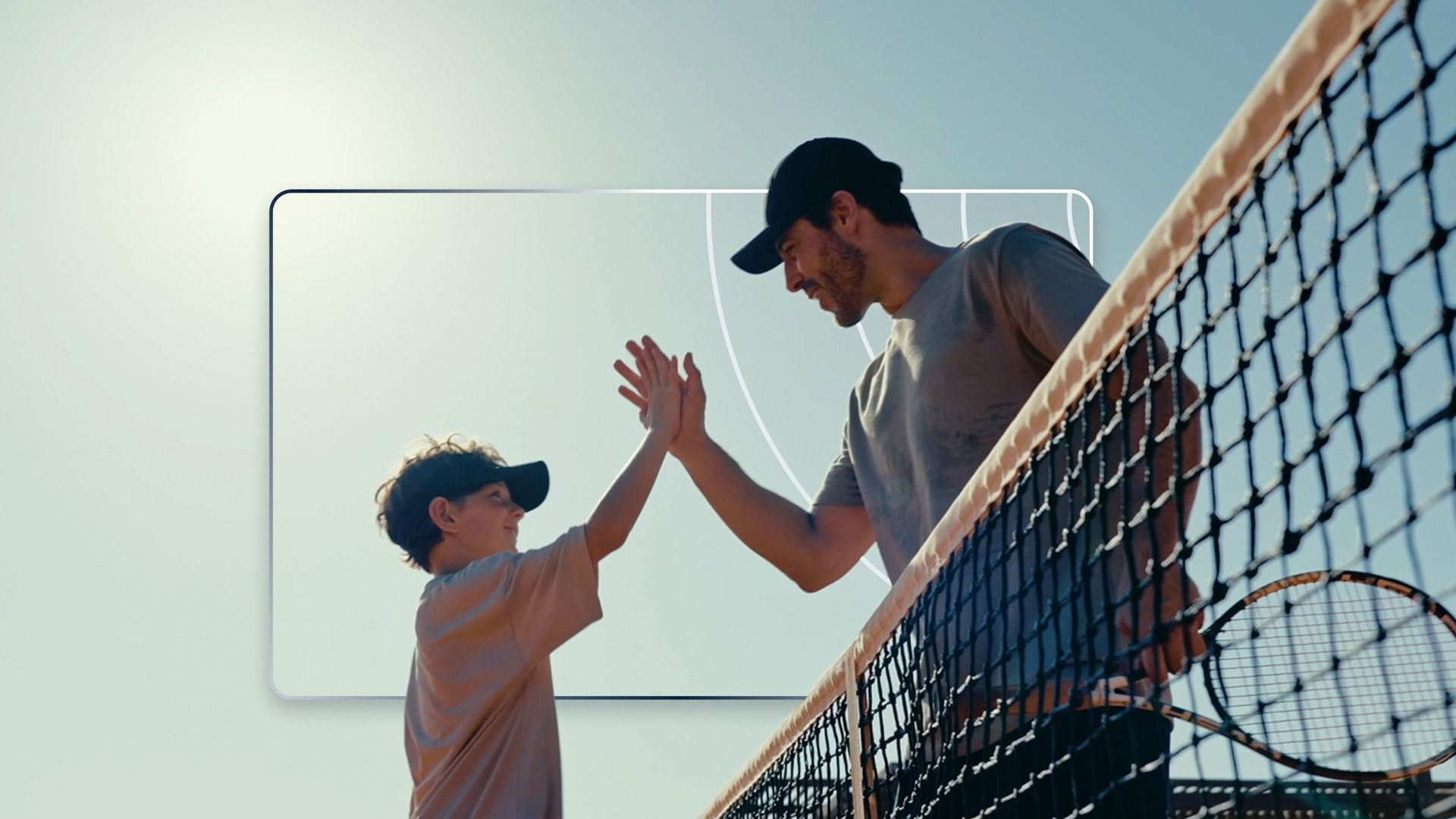 Otac i sin daju high-five preko teniske mreže nakon igre u Falkensteiner Group