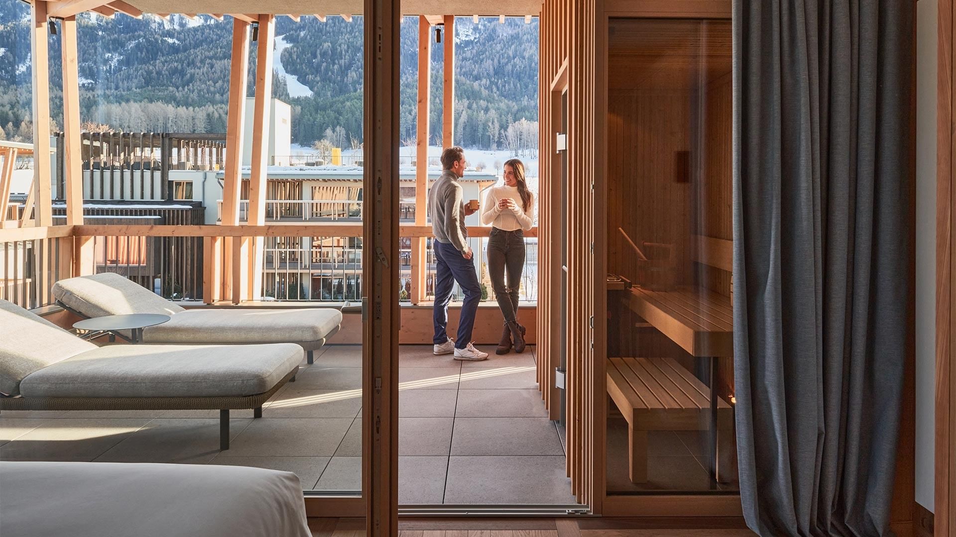 Coppia in terrazza con vista sulle montagne, sauna e lettini.