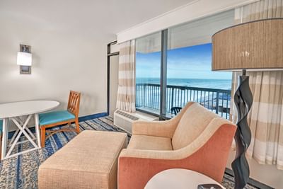 Ocean View Kitchenette room at Daytona Bahama House with chair, ottoman, table, and balcony overlooking the ocean.