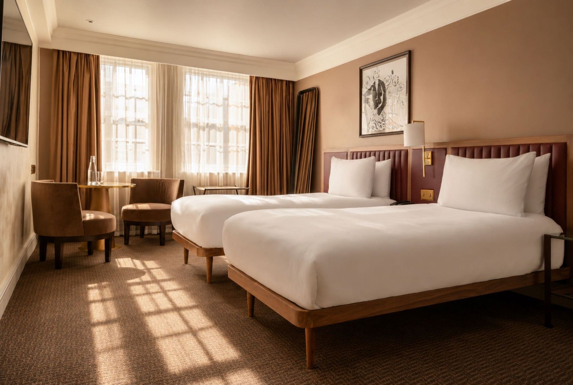 Bright Collection Deluxe Twin room with two beds, brown upholstered headboards, seating area, and large windows with drapes at The May Fair Hotel, London