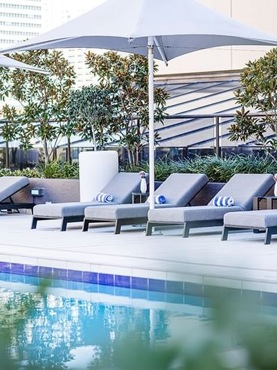 Poolside dining area with loungers and city view at Sofitel Brisbane Central