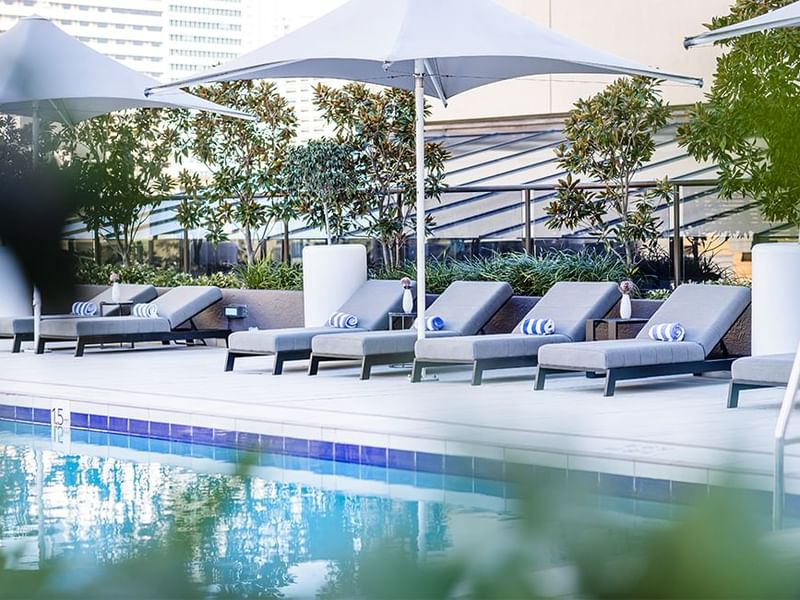 Poolside dining area with loungers and city view at Sofitel Brisbane Central