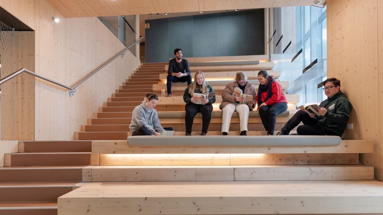 People reading on wooden stairs with integrated lighting at La Trobe University.