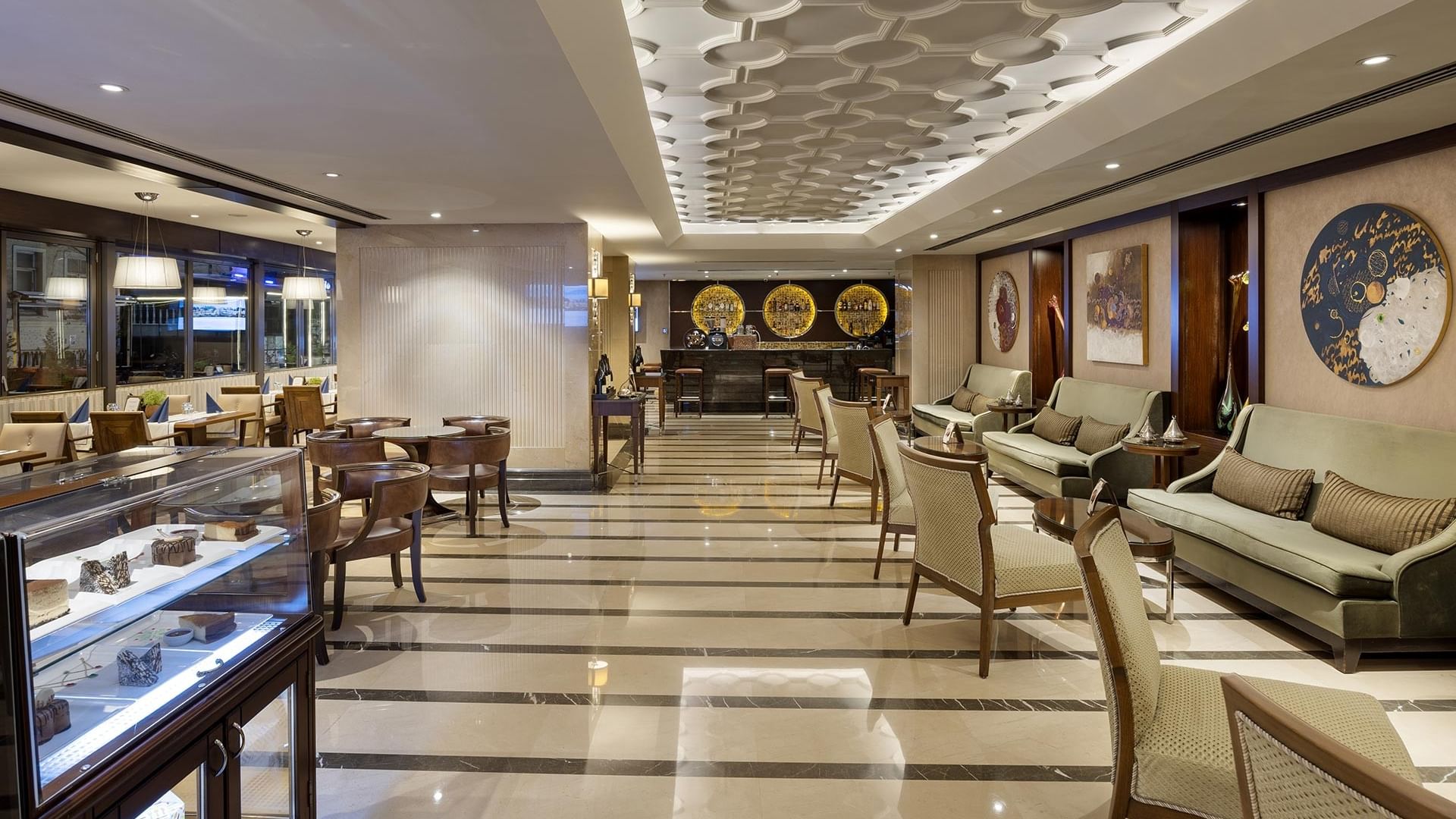 Pascarella Restaurant Café & Bar with patterned ceiling, striped floor, cushioned chairs, and a display case with desserts in Titanic City Taksim.