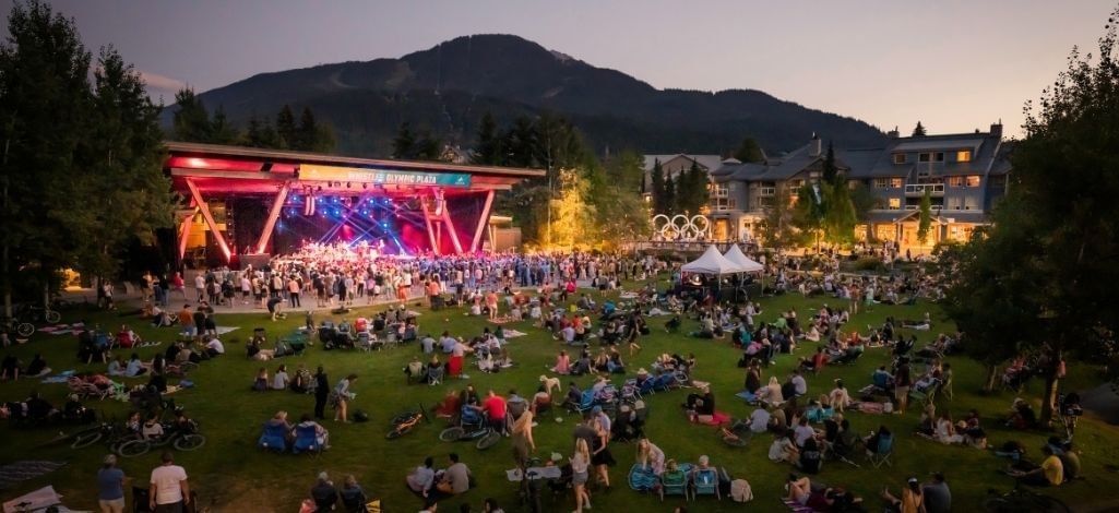 Outdoor concert at Whistler Olympic Plaza with guests gathered on the lawn.