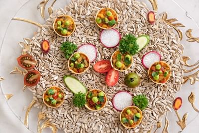 Platter featuring savory tarts filled with vegetables, surrounded by sunflower seeds and fresh garnishes at Park Hyatt Saigon