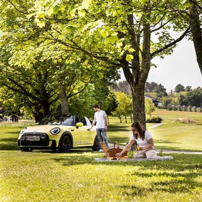 Couple preparing for a picnic beside a yellow car near Falkensteiner Balance Resort Stegersbach