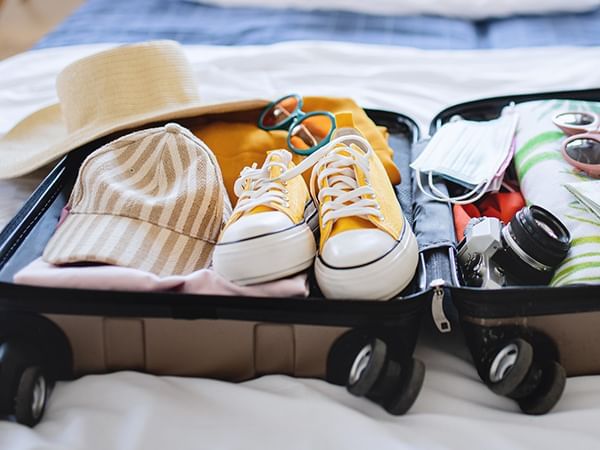 A suitcase packed with sunglasses and shoes on a bed at Lake Buena Vista Resort Village & Spa