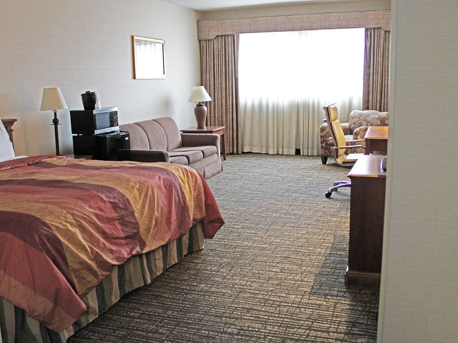 The Executive King Guest Room features a king bed, refrigerator, microwave, and a generous seating area with a sleeper sofa.