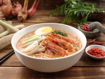 Bowl of laksa topped with shrimp & vegetables in White Rose Café at York Hotel Singapore