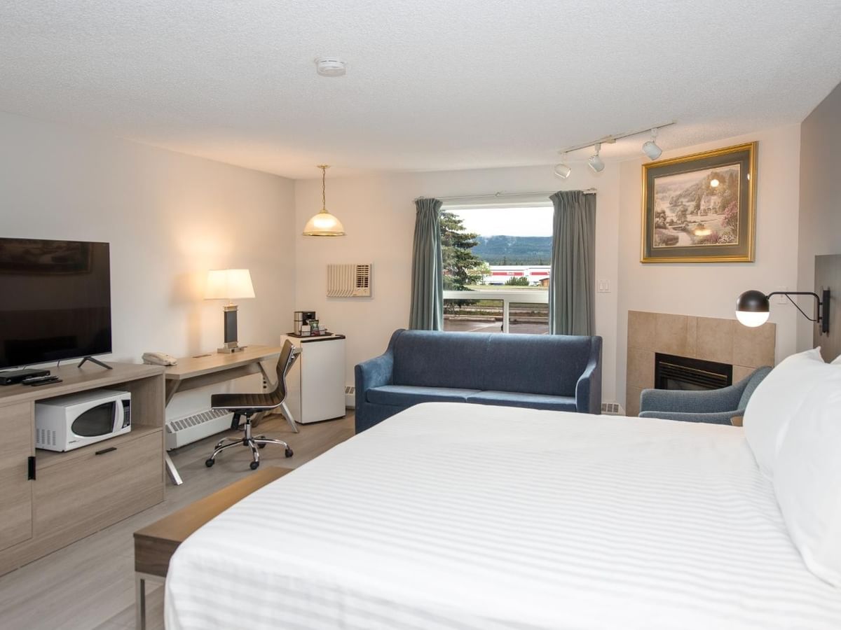 Hotel room with a large bed, desk, flat-screen TV, and blue couch.