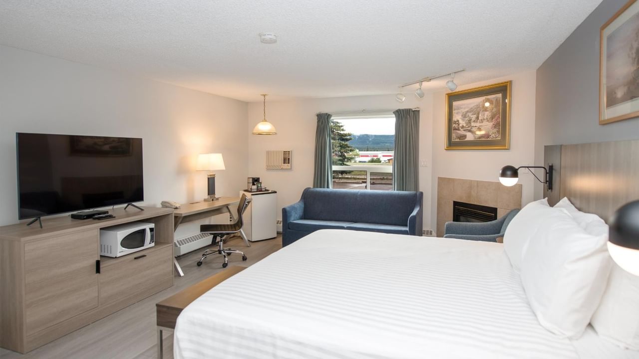 Hotel room with a large bed, desk, flat-screen TV, and blue couch.