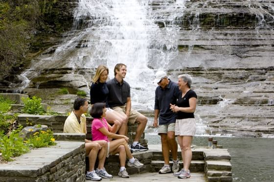 A group of people sitting on steps at Buttermilk Falls near La Tourelle Hotel and Spa