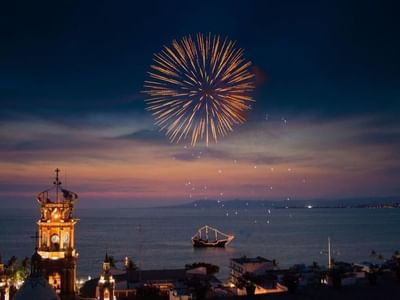 Vibrant golden fireworks bursting in the night sky over a boat on the dark ocean waters near Casa Dona Susana
