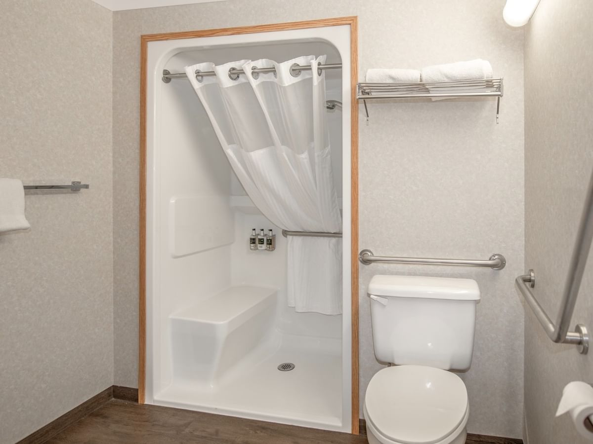 A bathroom with a toilet, shower stall, and towels.