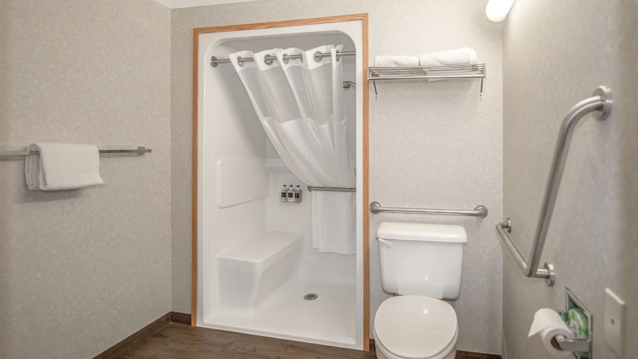 A bathroom with a toilet, shower stall, and towels.