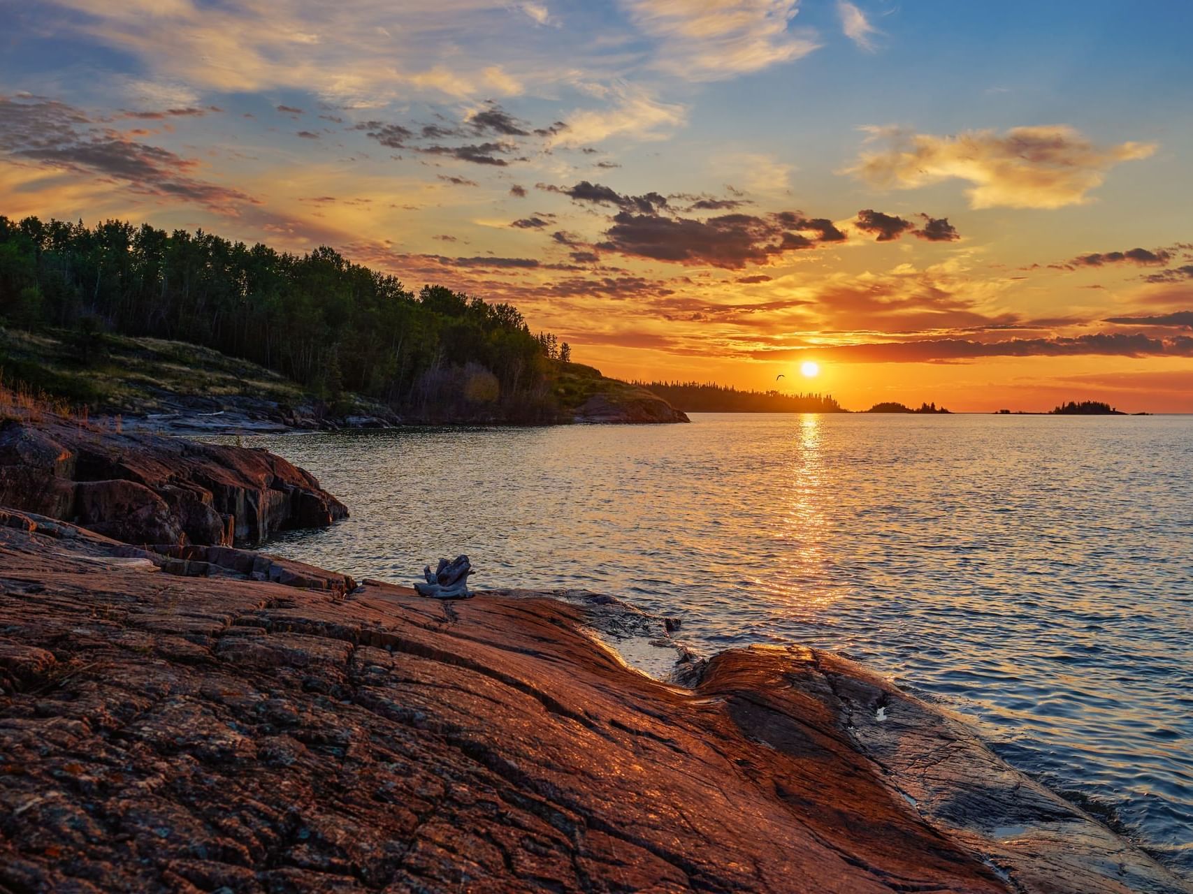 Sunset at rocky shore of Northern Lure near Merit Hotel & Suites