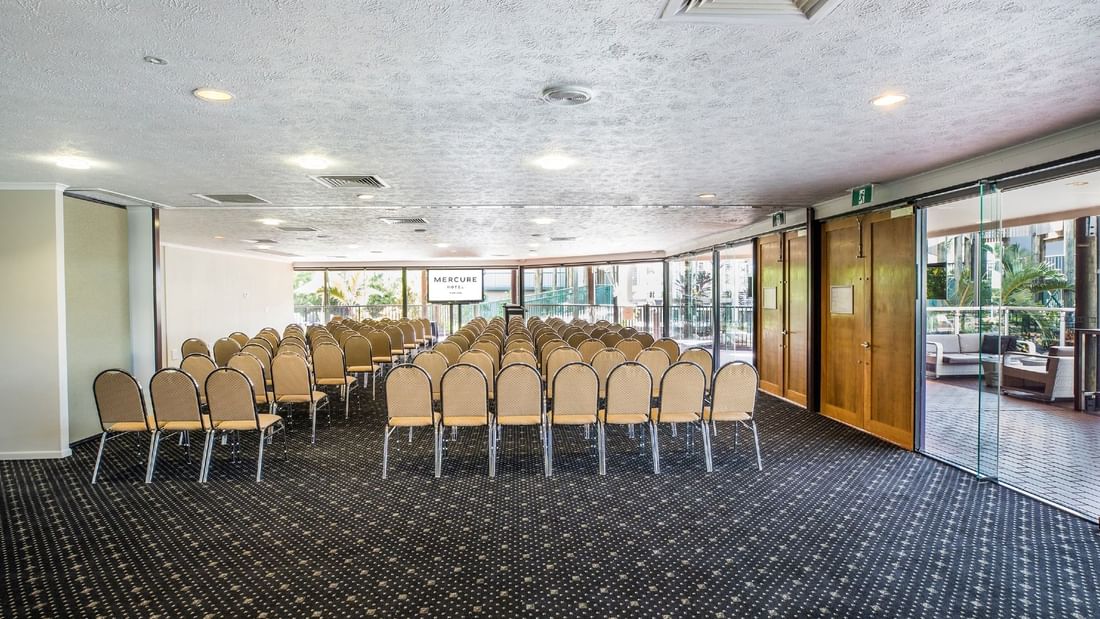Theatre style chair setup in Lakes Room featuring patterned carpet and large windows at Mercure Hotel Townsville