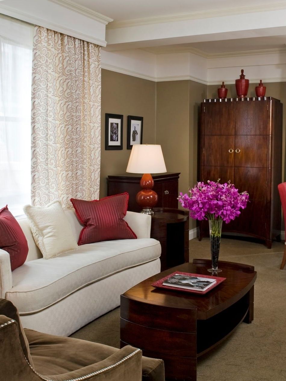 White sofa with red dining chairs, and purple flowers on the table in Hollywood Suite at Warwick New York 