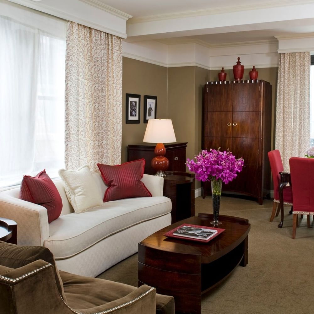 White sofa with red dining chairs, and purple flowers on the table in Hollywood Suite at Warwick New York 