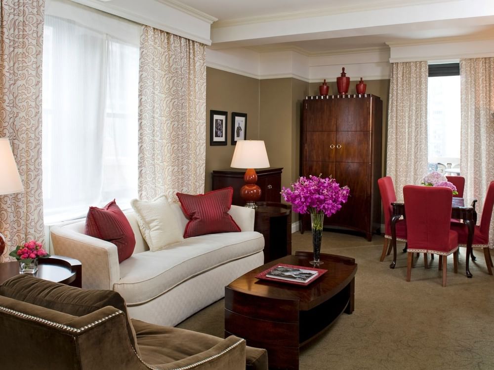 White sofa with red dining chairs, and purple flowers on the table in Hollywood Suite at Warwick New York 