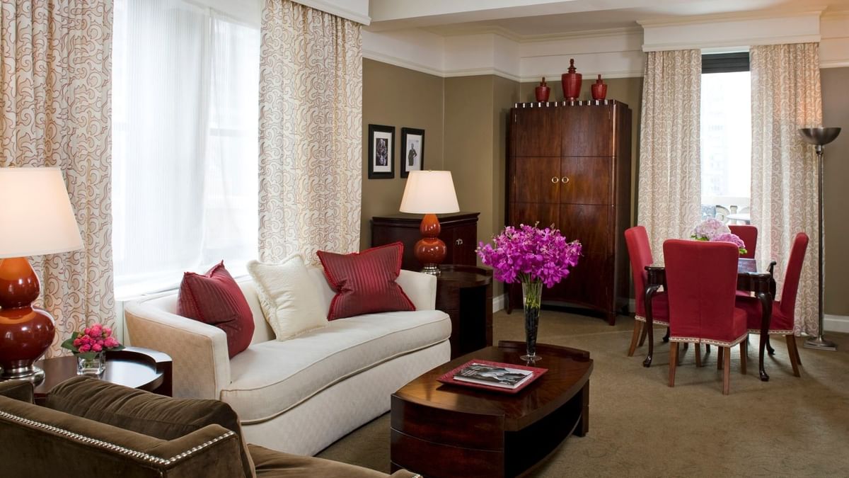 White sofa with red dining chairs, and purple flowers on the table in Hollywood Suite at Warwick New York 