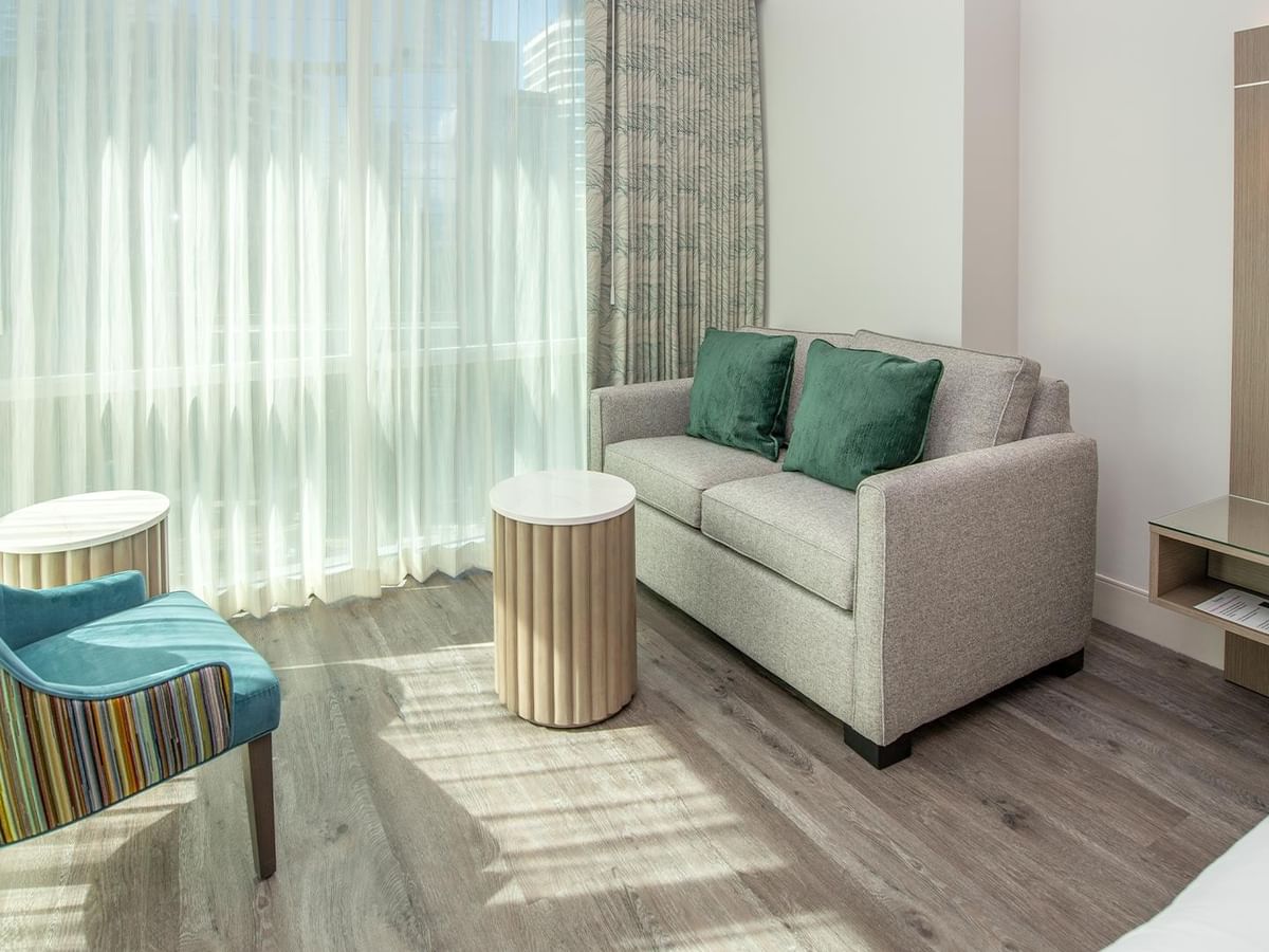 Room with gray couch, blue chair, and wooden floor.