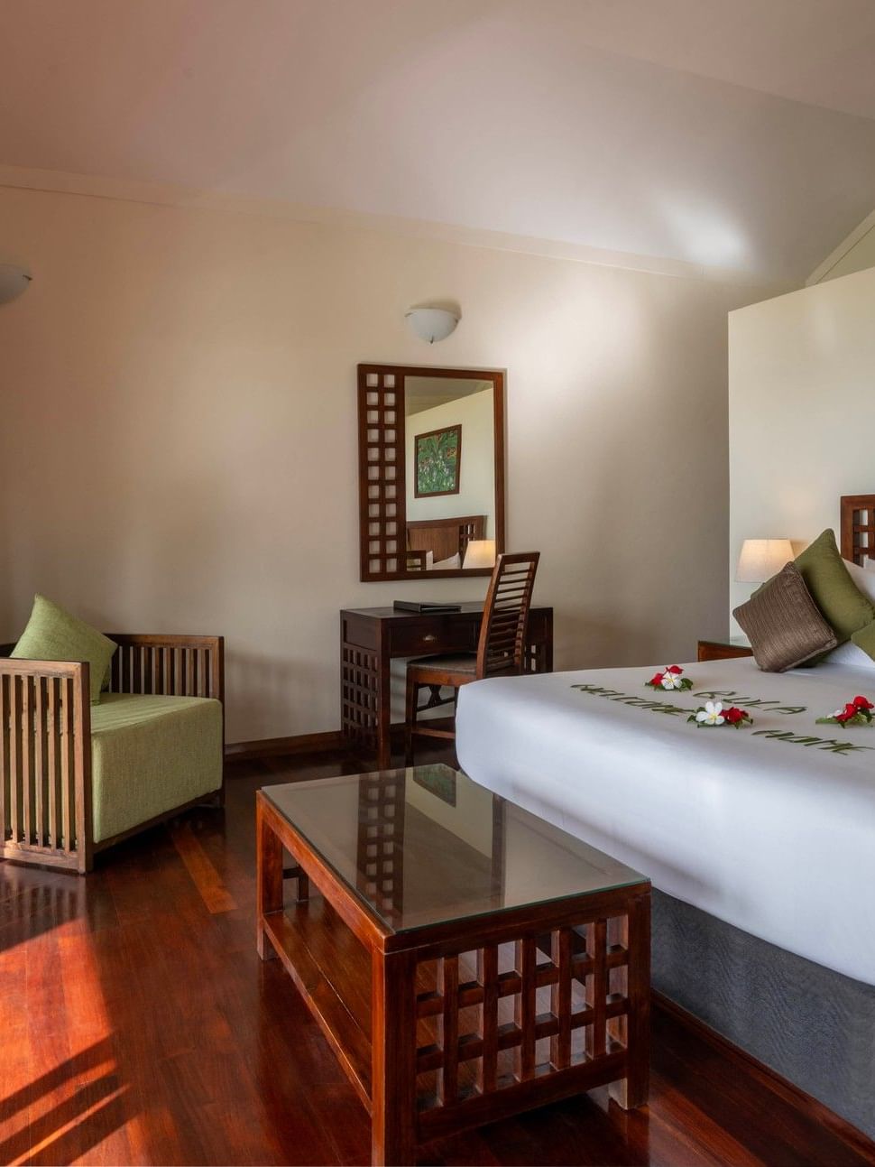 Polished wood floor by a master bed and green pillows near a vanity in Studio Villa at The Naviti Resort - Fiji