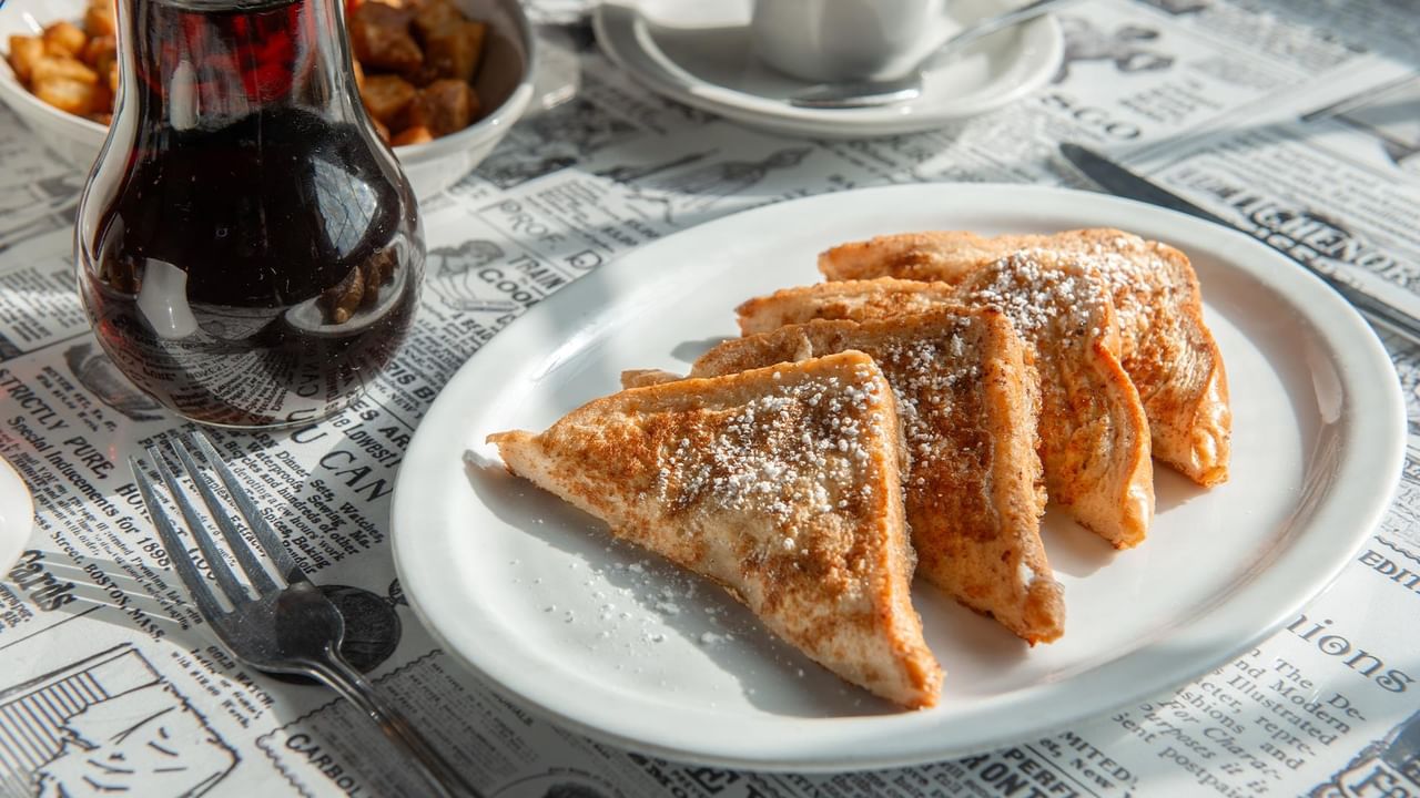 Plate of four French toast slices with powdered sugar.