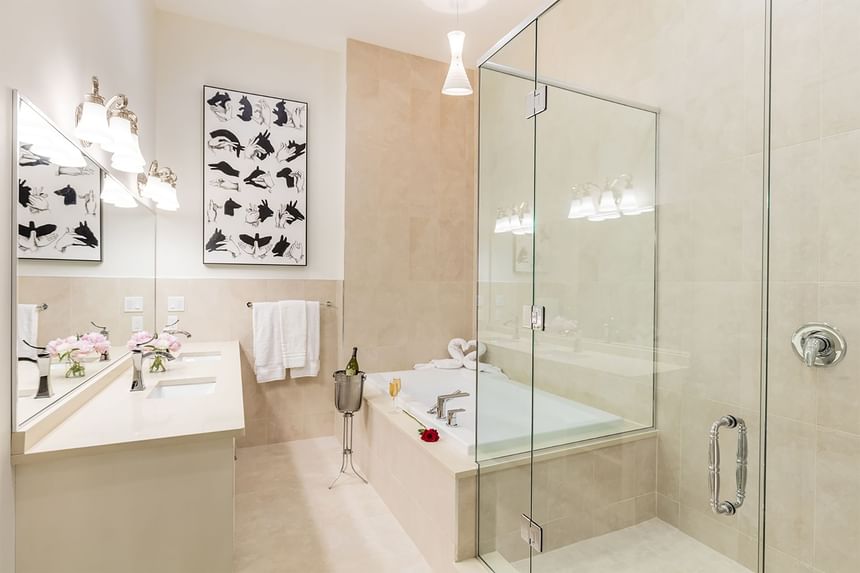 Bathroom vanity with large mirror, fresh flowers, shower area & bathtub in Presidential Room at Retro Suites Hotel